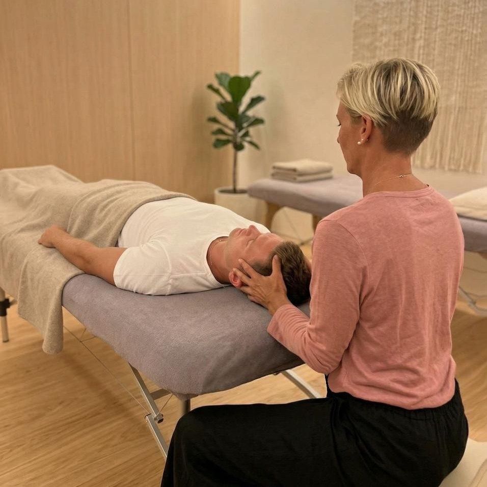 Christiane behandelt eine liegende Person craniosacral am Kopf